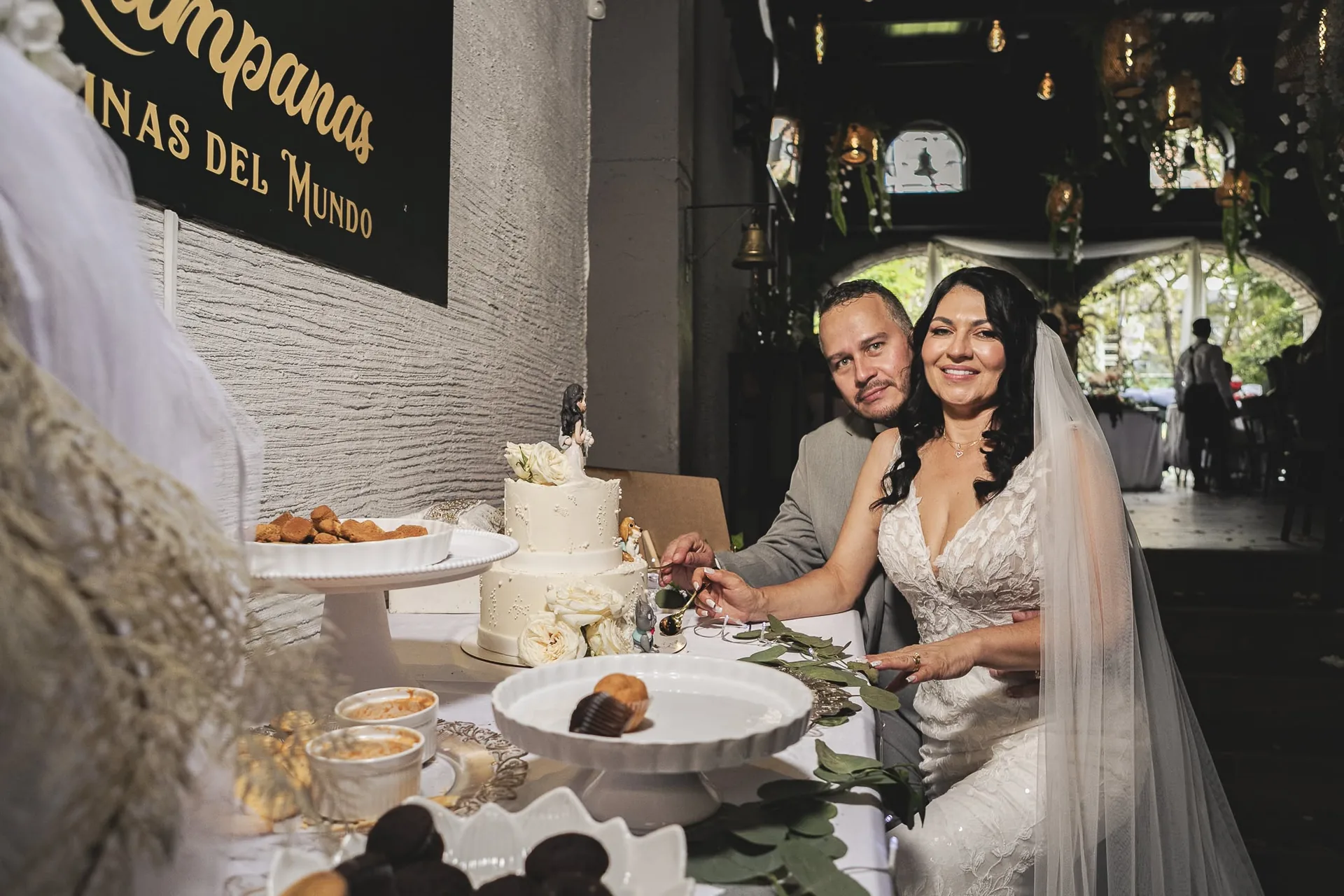 Los novios partiendo la torta frente al logo de Kampanas