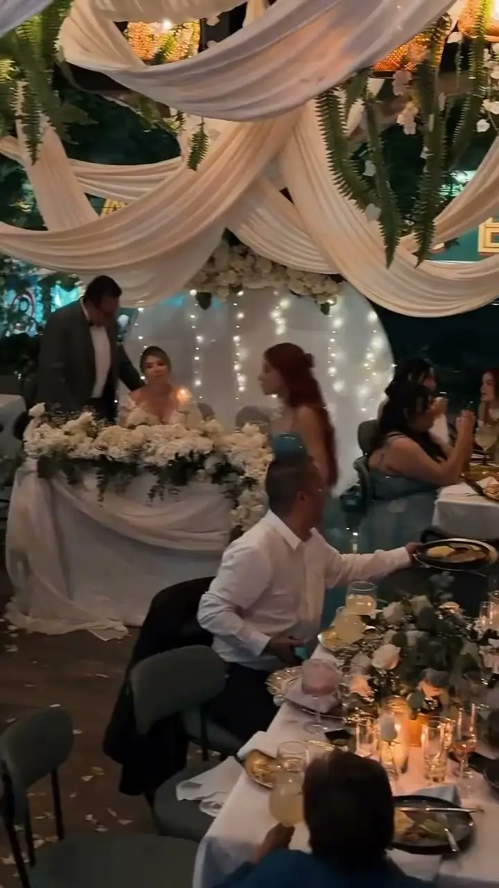 La mesa principal de los novios, con flores blancas y luces, durante una boda en Kampanas