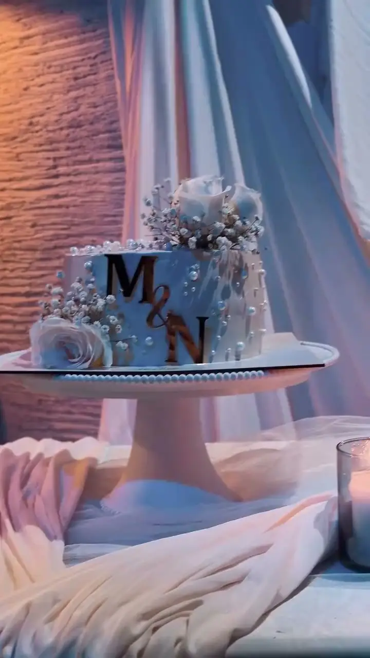 El pastel de matrimonio con las iniciales de los novios, entre velas, en el salón de Kampanas